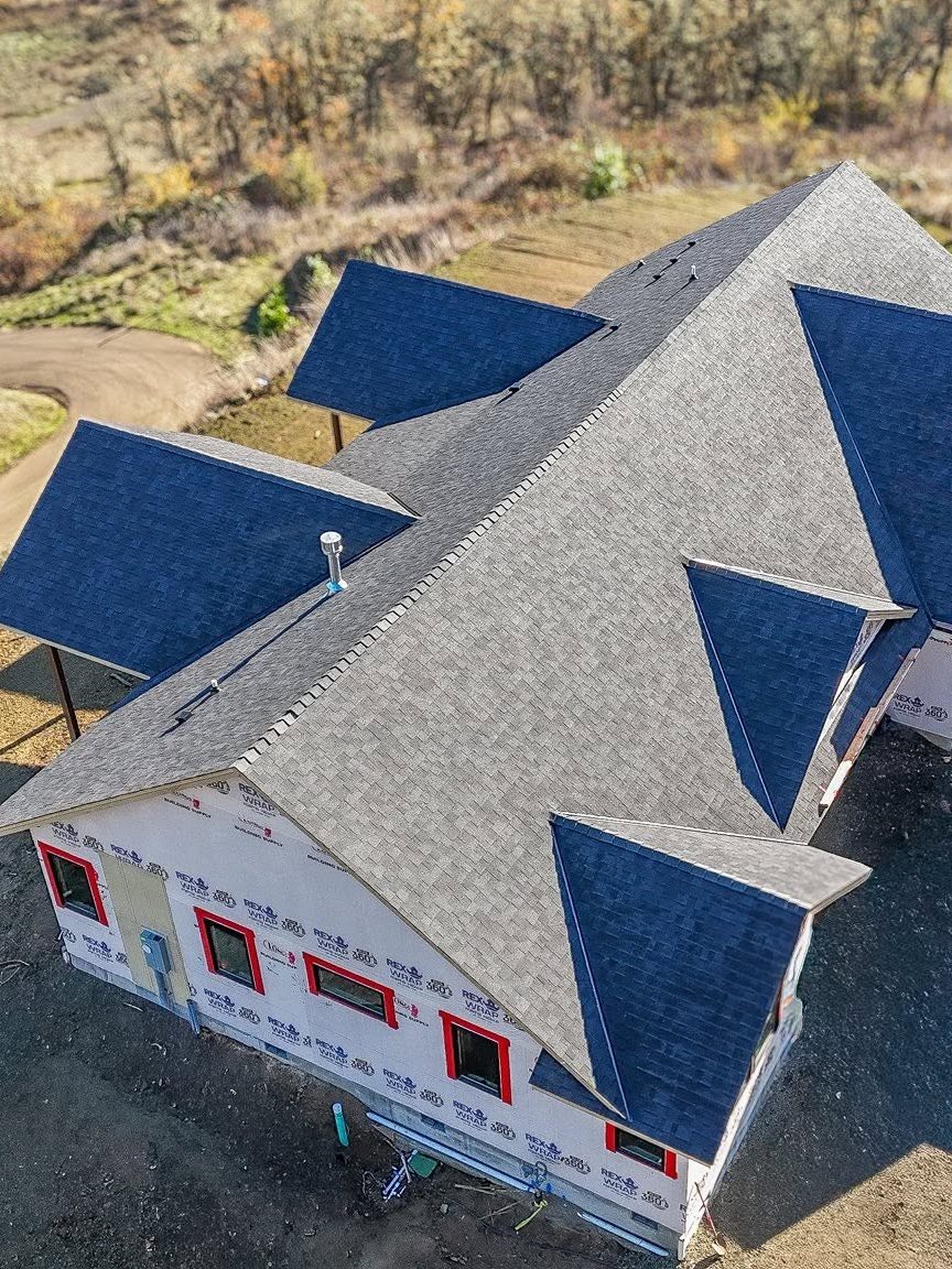 A new shingle roof and gutters on a red barn by Rosales Roofing & Construction